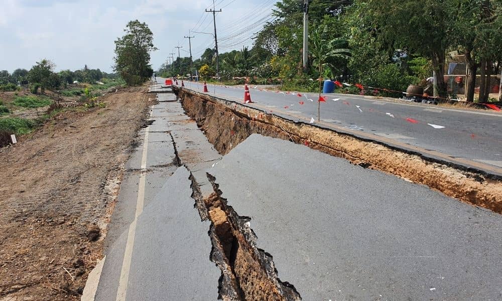 A civil engineer inspecting a road collapse to identify ground failure and structural risks beneath the pavement