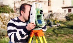 Surveyor using a total station to measure a residential lot in Nashville for a topographic survey