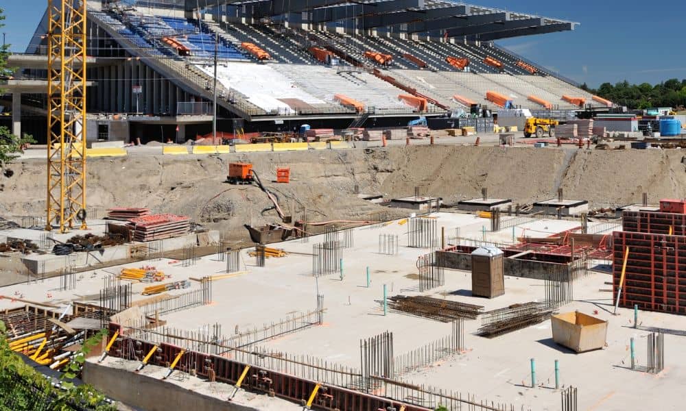 Wide shot of a stadium under construction with cranes and steel framework during a construction survey