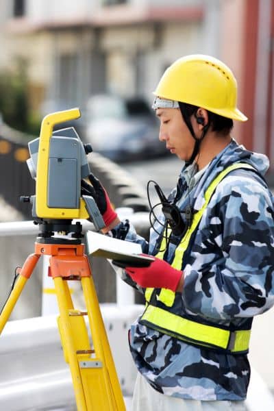 Licensed land surveyor using equipment to prepare an elevation certificate for a residential property.
