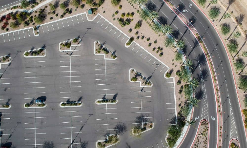 A drone surveying image showing a city parking lot beside a landscaped green area, highlighting the contrast between asphalt and vegetation.

