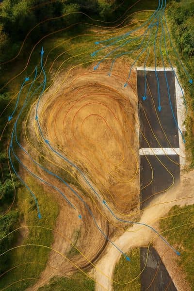 A drone surveying map showing elevation contours and drainage flow across a redeveloped site.

