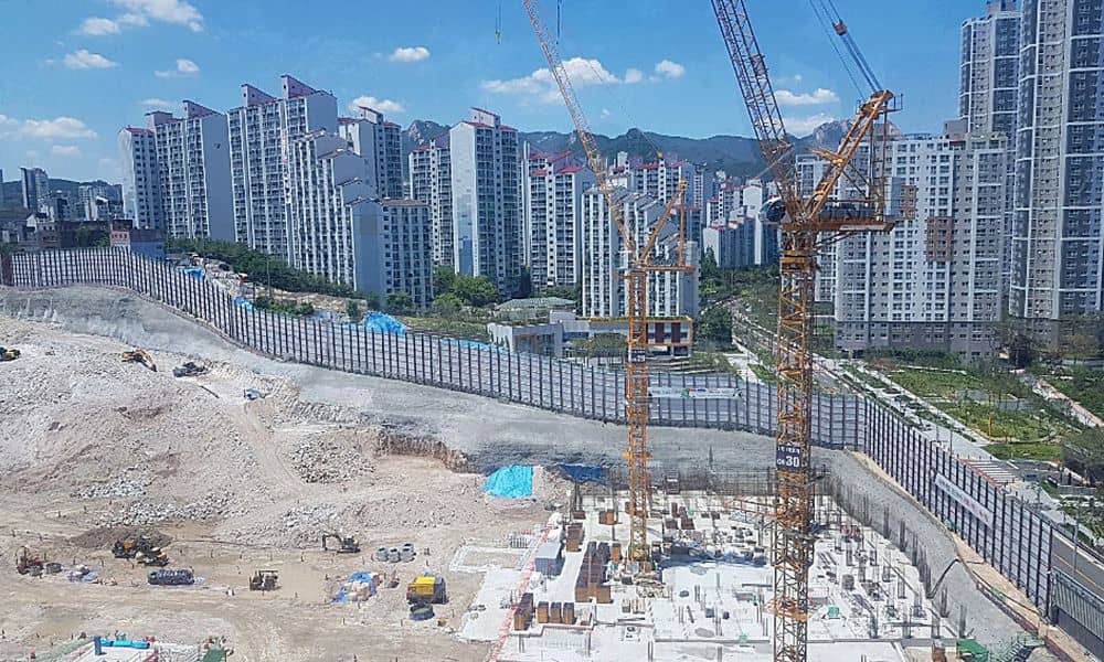 A large construction site beside a dense urban district showing how major projects can shift modern urban planning and reshape surrounding communities