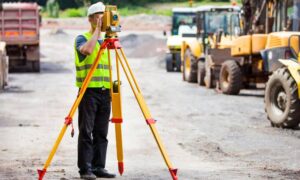 Commercial land surveyor on construction site - ALTA SURVEY Nashville A land surveyor conducting a due diligence survey on a commercial construction site to verify property conditions before purchase