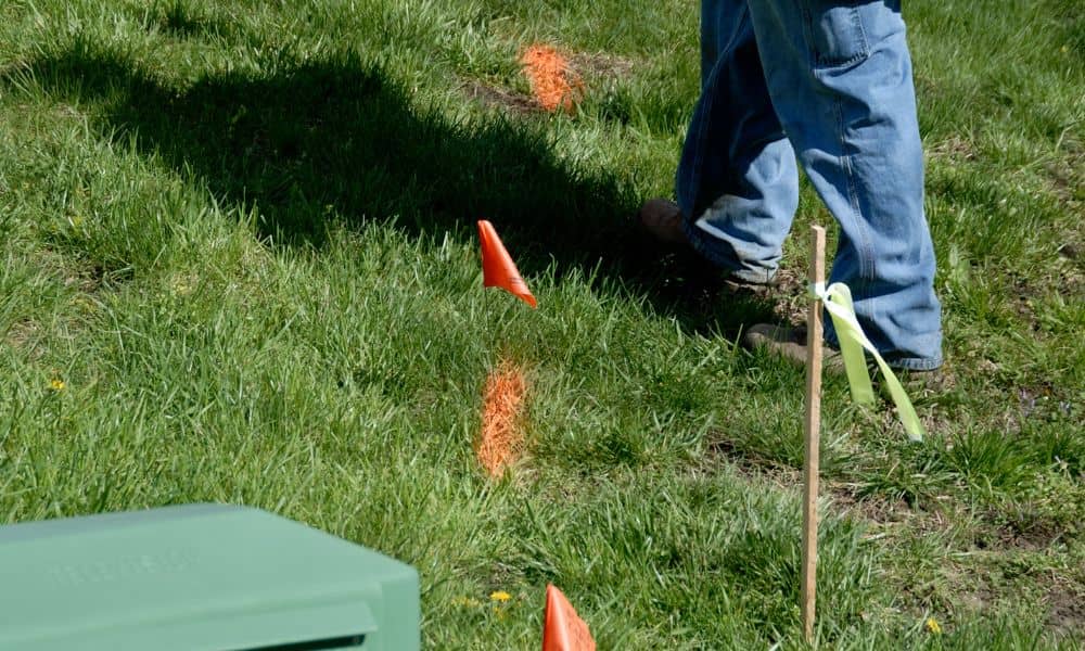 Land surveyor marking property boundaries with stakes and flags in a residential yard