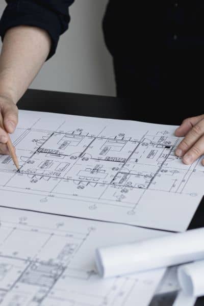 A consulting engineer reviews detailed site plans and technical drawings for a high-risk infrastructure project.