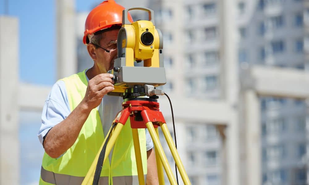 Surveyor using a total station to collect measurements for an ALTA survey at a commercial property site
