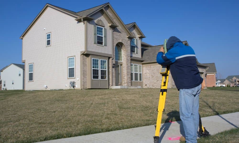 A surveyor measuring a residential property to check boundaries and plan a home survey
