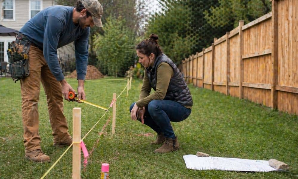 Homeowner and contractor reviewing fence placement along a marked property line with guidance from a licensed surveyor