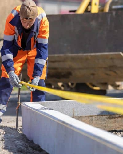 Worker measuring layout on a construction site to make sure everything lines up before building begins