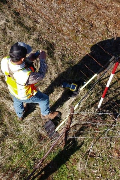 Licensed surveyor using GPS equipment to verify property boundaries before fence installation